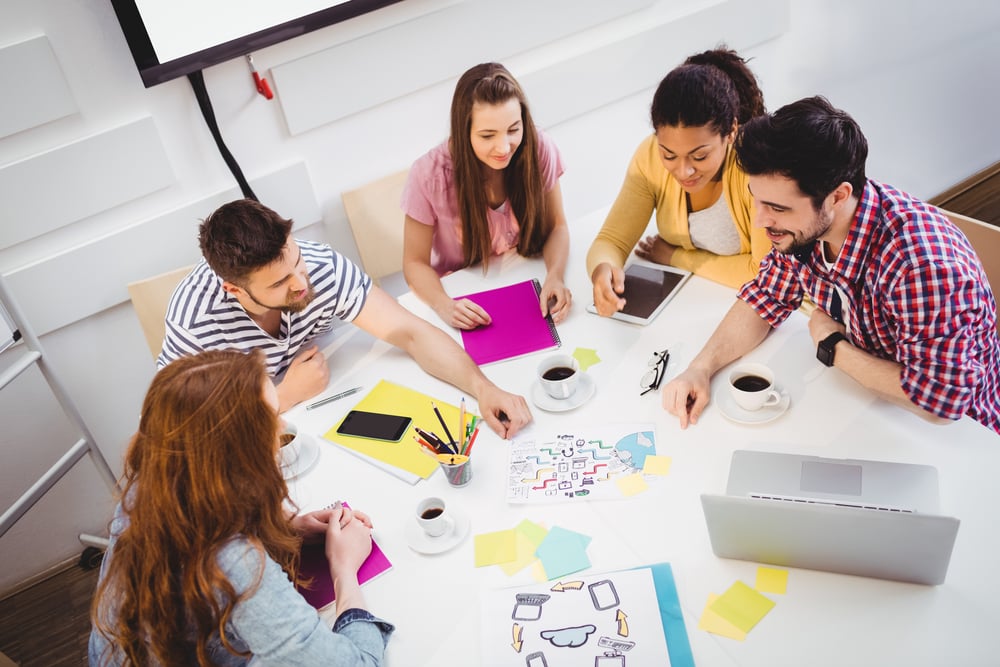 High angle view of young business people discussing in meeting at creative office